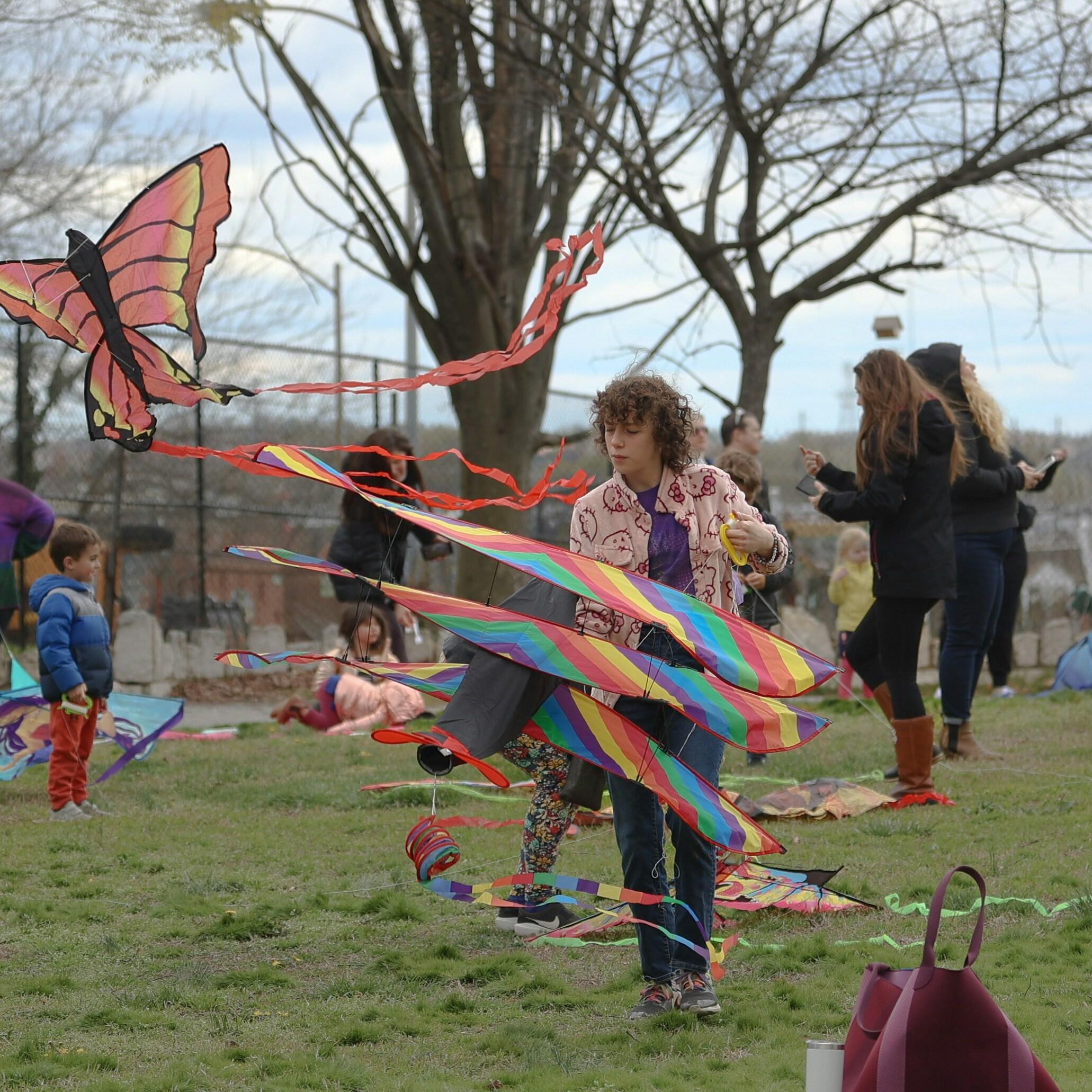 A community event with a teenage boy who has a bright kite